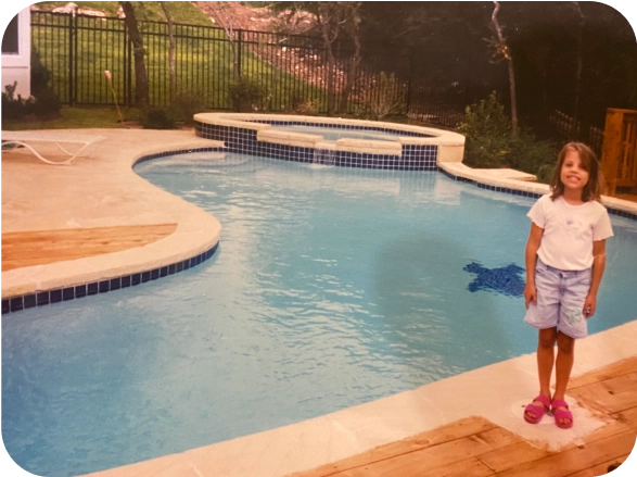 Photo of owner Britney as a child, standing next to a pool.